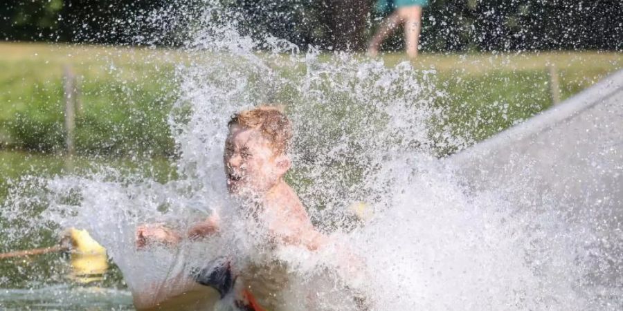 So lässt sich die Hitze aushalten: Ein Junge rutscht eine Wasserrutsche hinunter. Foto: Thomas Warnack/dpa