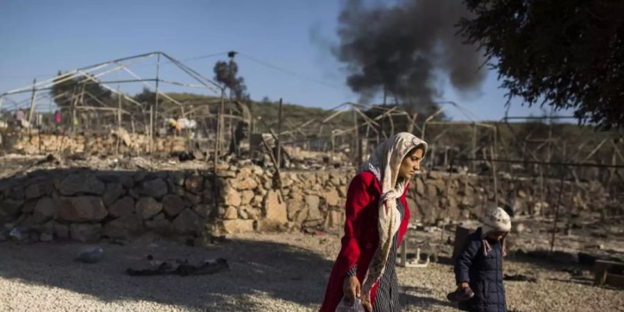 Eine Frau geht mit ihrem Kind durch das ausgebrannte Flüchtlingslager Moria. Foto: Socrates Baltagiannis/dpa