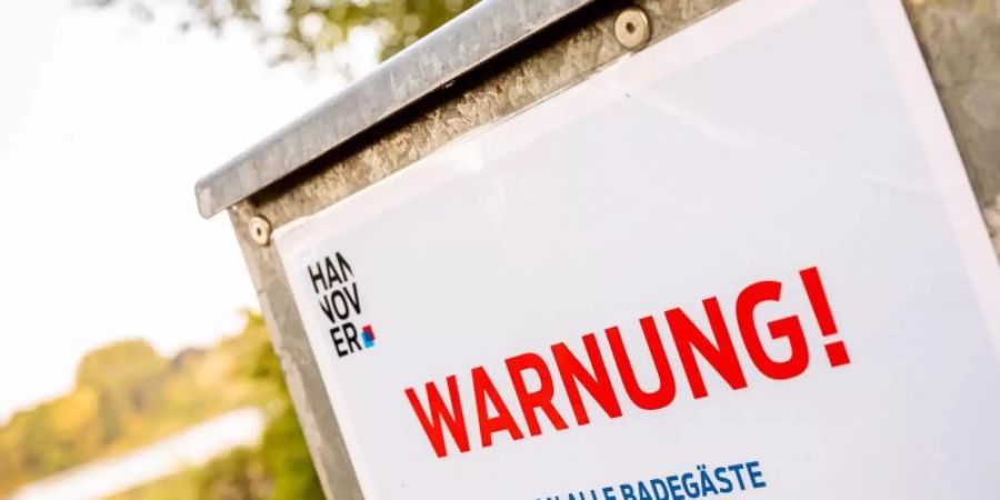 Ein Hinweisschild warnt Badegäste vor Blaualgen. Sommerliche Temperaturen können Ursache eines starken Wachstums sein. Foto: Moritz Frankenberg/dpa