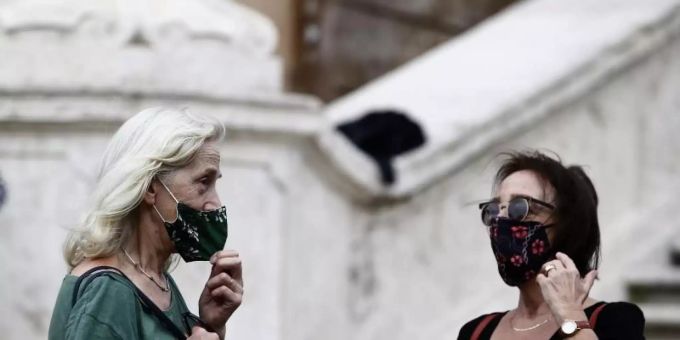 Zwei Frauen mit Masken stehen vor einer Treppe in Rom. Corona italien