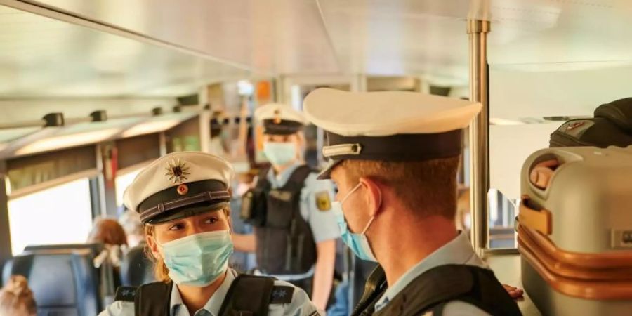 Beamte der Bundespolizei und Mitarbeiter der DB Sicherheit kontrollieren in einem ICb die coronabedingte Maskenpflicht. Foto: Annette Riedl/dpa