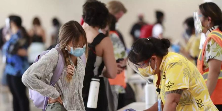 Eine Reisende auf Hawaii lässt sich vor einem Test beraten. Foto: Marco Garcia/AP/dpa