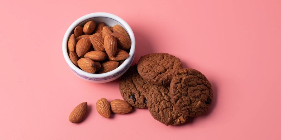 nüsse und cookies vor rosa hintergrund