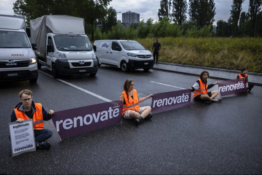 Aktivisten von Renovate Switzerland blockieren eine Strasse.