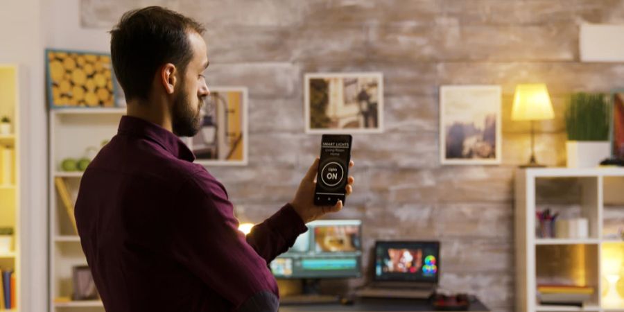 Mann Smartphone Wohnzimmer Glühbirne smarte Einstellung