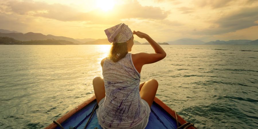 Frau, die bei Sonnenuntergang mit dem Boot zwischen den Inseln unterwegs ist.
