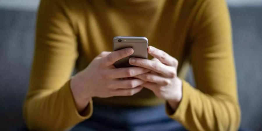 Eine junge Frau hält ein Smartphone in der Hand. Lustige Memes können Menschen dabei helfen, den mit der Corona-Pandemie verbundenen Stress besser zu bewältigen, indem sie deren Stimmung aufhellen. Foto: Fabian Sommer/dpa