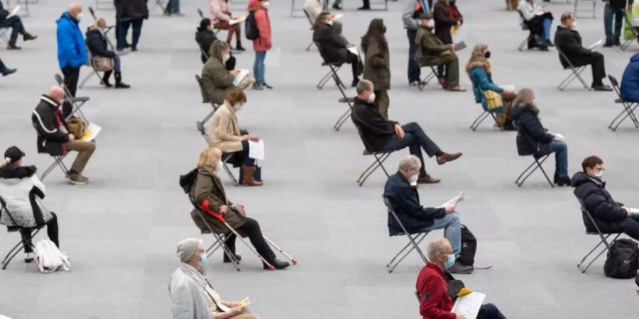 Menschen sitzen am ersten Tag des Impfmarathons in der August-Schärttner-Halle in Hanau und warten darauf, dass sie geimpft werden. Foto: Sebastian Gollnow/dpa