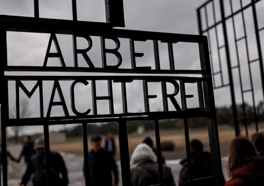 Besucher betreten das Gelände durch das Tor mit dem berüchtigten Slogan «Arbeit macht frei» während einer Gedenkfeier im ehemaligen Konzentrationslager Sachsenhausen bei Berlin, Deutschland, am 23. April 2023.