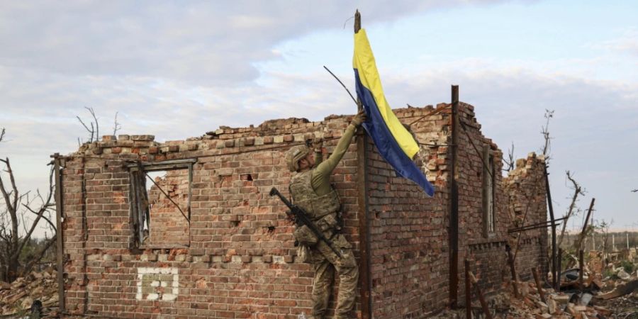 Ein ukrainischer Kommandeur hisst die Nationalflagge als Symbol der Befreiung des Frontdorfes Andrijewka in der Region Donezk. Foto: Alex Babenko/AP/dpa