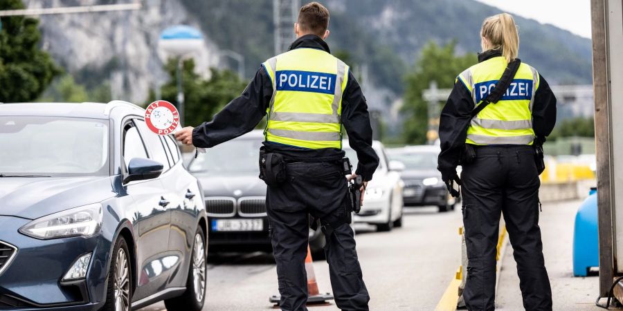 Deutsche Bundespolizisten beobachten an der Grenze zu Österreich auf der Autobahn A93 den Verkehr.