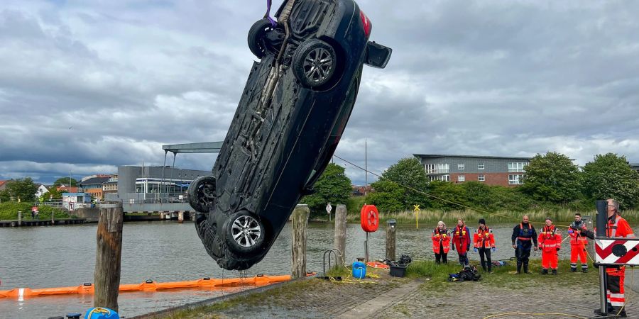 Einsatzkräfte ziehen mit einem Kran ein Auto aus dem Husumer Hafenbecken.
