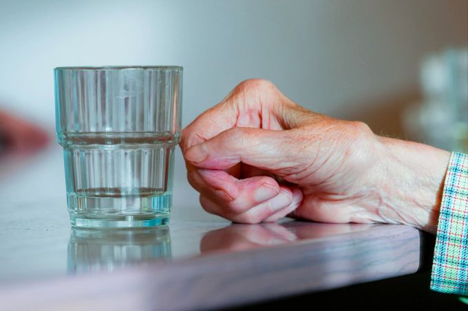 Una persona mayor y un vaso de agua.