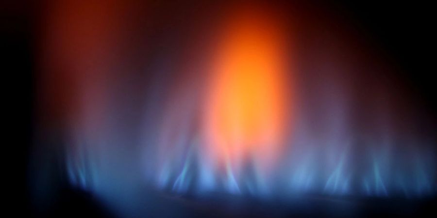 Eine Gasflamme ist hinter dem Sichtfenster eines Gas-Durchlauferhitzers.