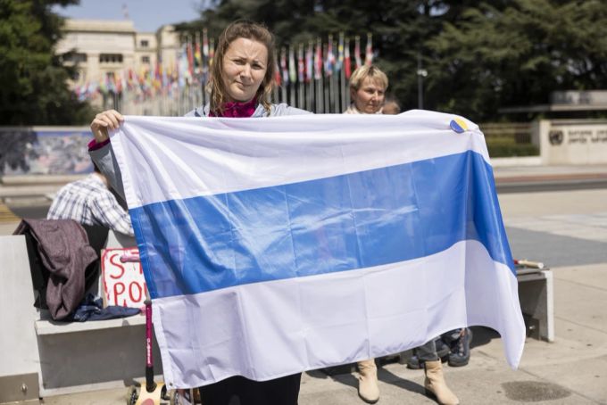 Demonstranten in Genf tragen die blau-weisse Fahne, die in Russland zu einem Symbol von Kriegsgegnern geworden ist. Genf