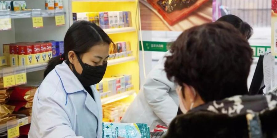 Eine Apothekerin verkauft in Wuhan Atemschutzmasken. Die chinesische Stadt gilt als Ausgangspunkt der neuartigen Lungenkrankheit. Foto: Dake Kang/AP/dpa