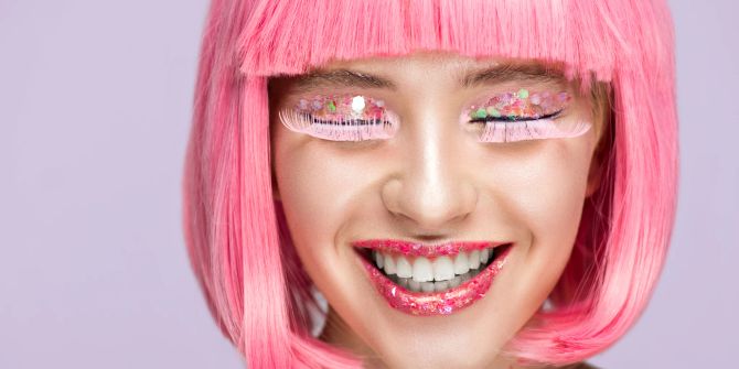 Lächelnde Frau mit rosafarbenen Haaren und Wimpern
