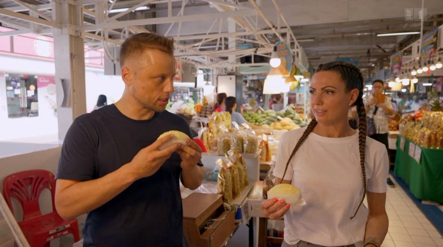 Jan Fitze beisst in die Durian-Frucht. Viola Tami würgt.