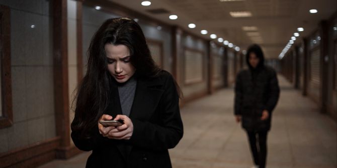 Mädchen mit Smartphone wird vom Stalker verfolgt