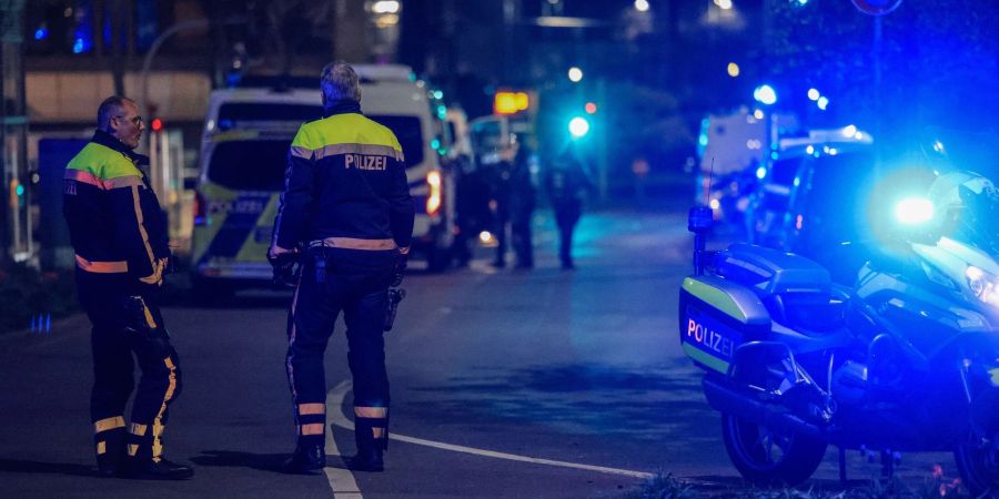 Polizisten sperren in Duisburg vor einem Tatort in einem Fitnessstudio die Strasse.