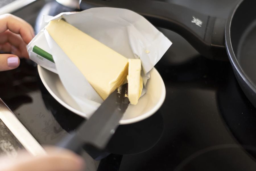 Eine Person schneidet ein Stück Butter ab. (Symbolbild)