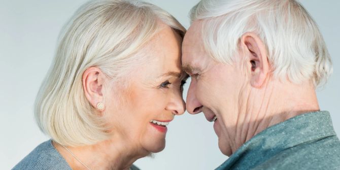 älterer frau, älterer mann, lächeln sich gegenseitig an, weisser hintergrund