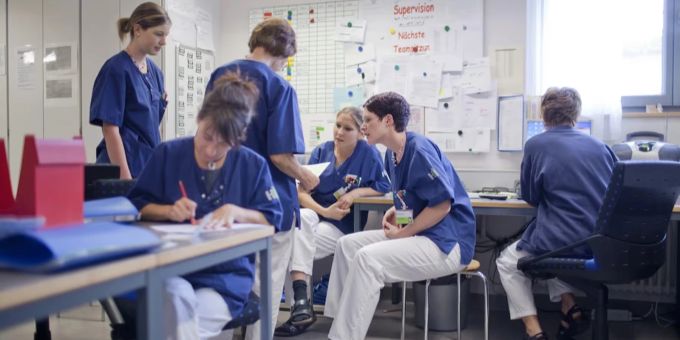 Das Schweizer Gesundheitssystem kämpft nach wie vor mit einem Personalmangel. Pflegende sitzen auf Stühlen