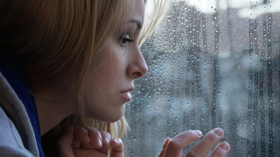 Frau sieht traurig aus dem Fenster