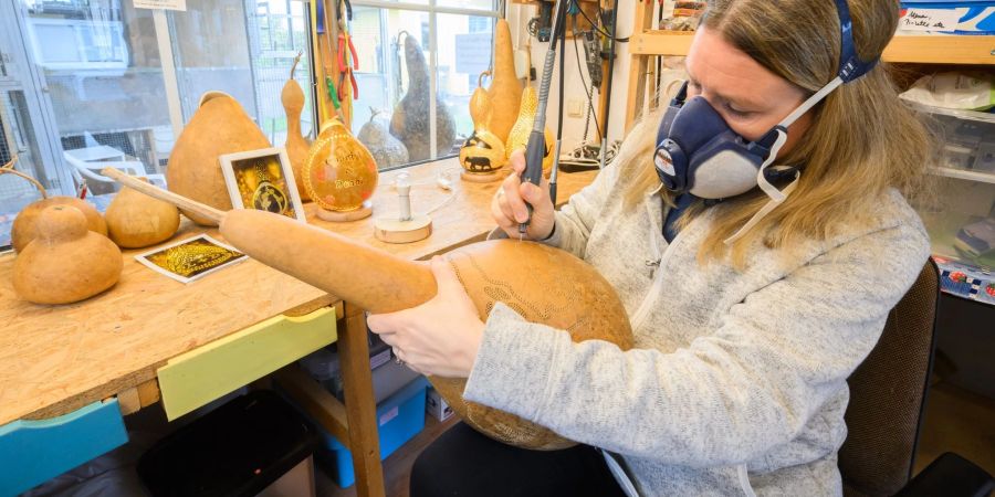 Virginia Lauterbach bearbeitet in ihrer Werkstatt einen Flaschenkürbis mit einem Bohrer.
