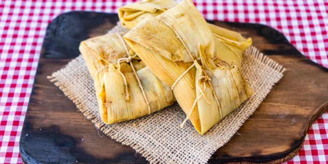 Traditionelle Anden-Mais-und Fleisch-Tamales auf einem Holzbrett serviert.