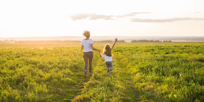 Mutter und Tochter laufen fröhlich auf einer Wiese