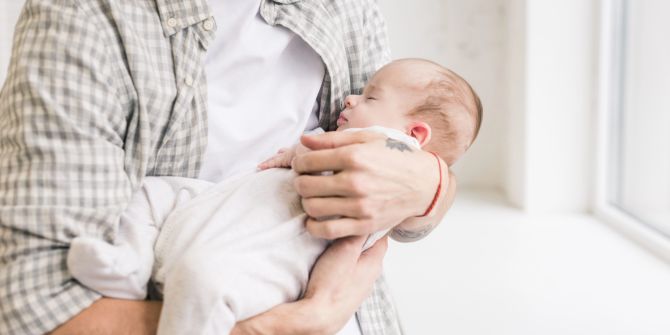 Schlafendes Baby auf dem Arm des Vaters