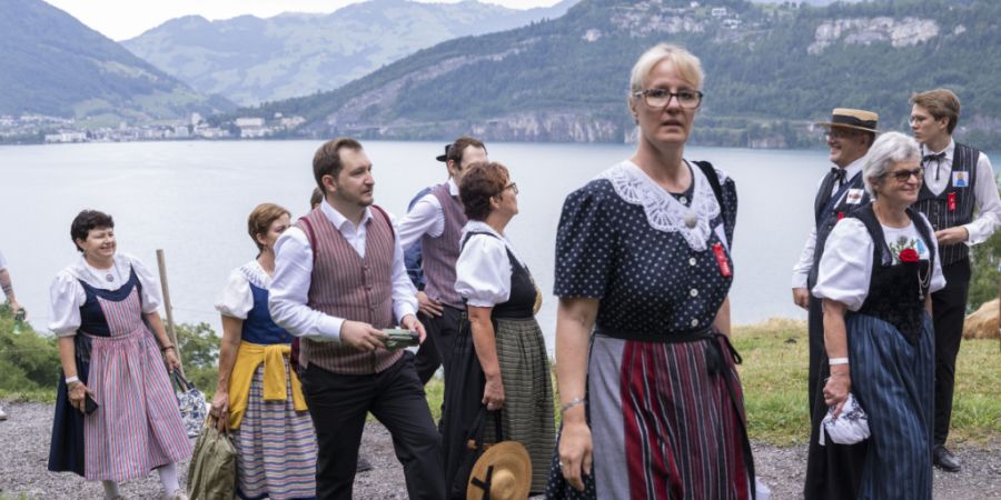 Menschen in farbigen Trachten treffen auf dem Rütli ein.