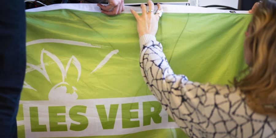 Delegierte hängen ein Transparent am Rednerpult an der Delegiertenversammlung der Grünen Schweiz in Chur auf.