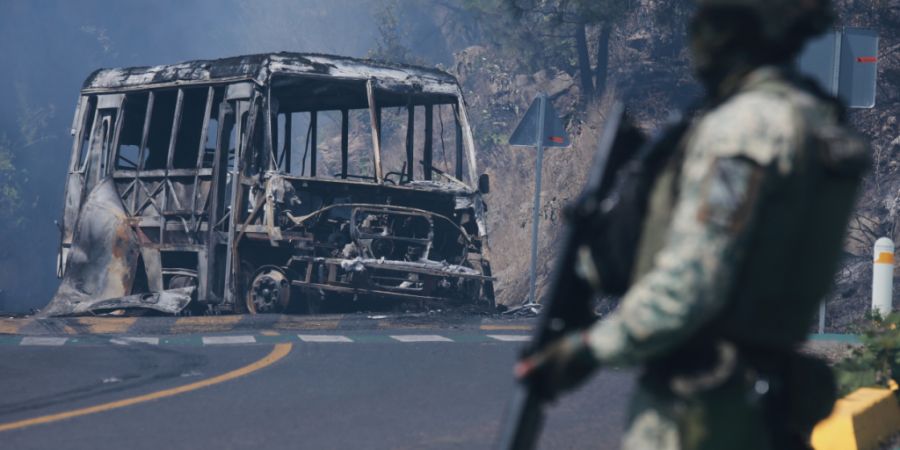 dpatopbilder - Ein Soldat steht neben einem ausgebrannten Bus, der in Cointzio nach dem Tod von «El Mencho» in Brand gesetzt wurde. Foto: Armando Solis/AP/dpa