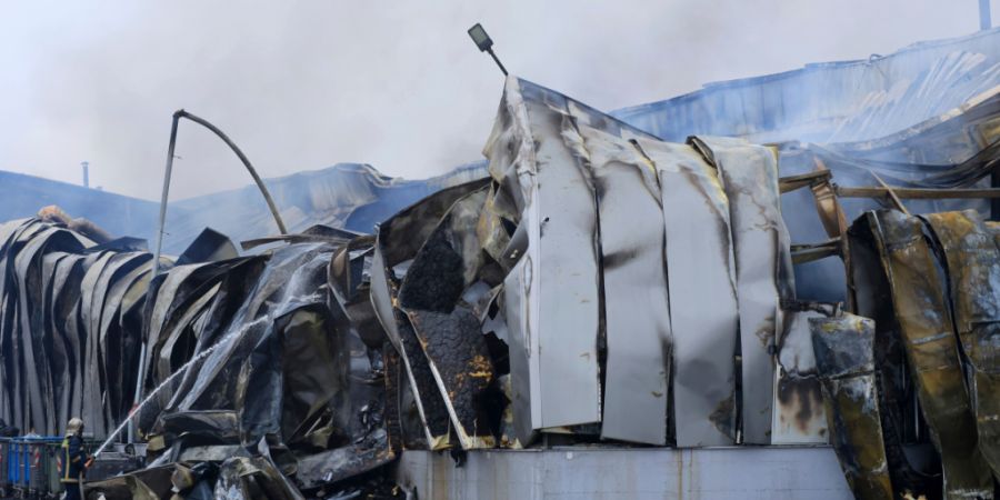 dpatopbilder - Ein Feuerwehrmann versprüht Wasser nach einer Explosion und einem Brand in einer Keksfabrik in Trikala. Foto: George Kidonas/InTime News/AP/dpa