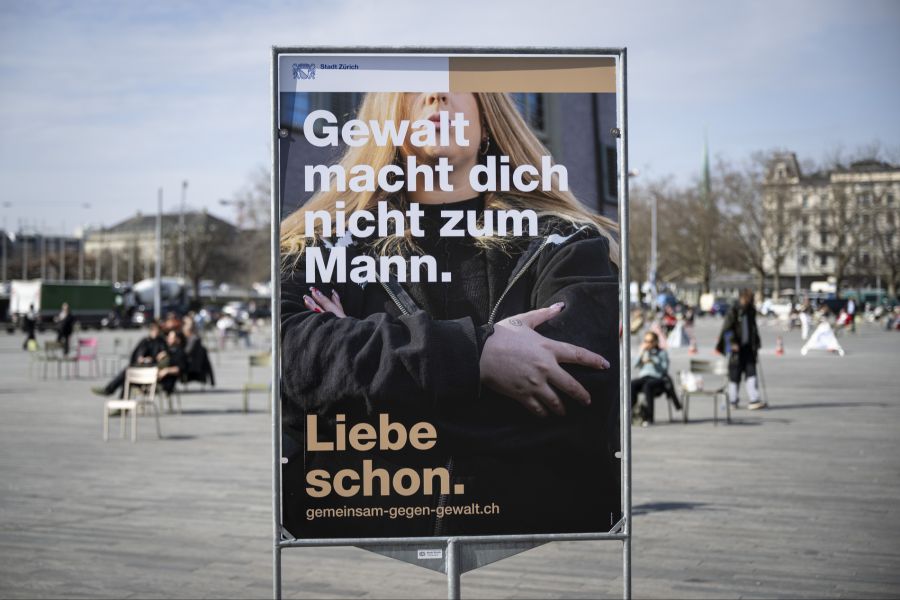 Das Sujet ist immer dasselbe. Im Hintergrund sind Personen mit verschränkten Armen zu sehen.