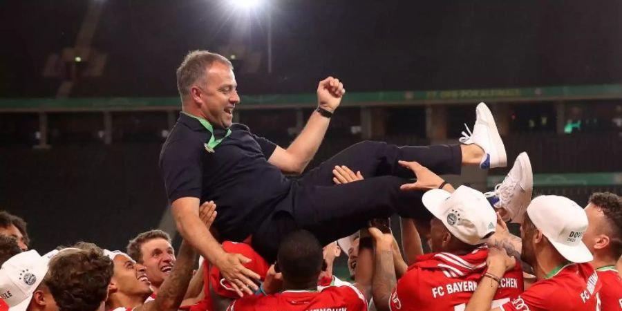 Münchens Trainer Hansi Flick wird von seinen Spielern in die Luft geworfen. Foto: Alexander Hassenstein/Getty Images Europe/Pool/dpa