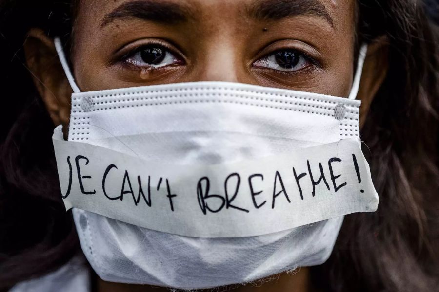 Eine Demonstrantin weint bei einem Protest und trägt einen Mundschutz auf dem eine Nachricht fixiert ist mit den Worten: «i can't breathe».