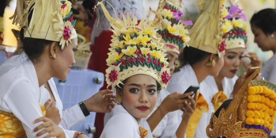 Balinesische Tänzerinnen und Tänzer in traditioneller Kleidung warten auf ihren Auftritt beim Kuningan-Fest in einem Hindu-Tempel. Foto: Firdia Lisnawati/AP/dpa