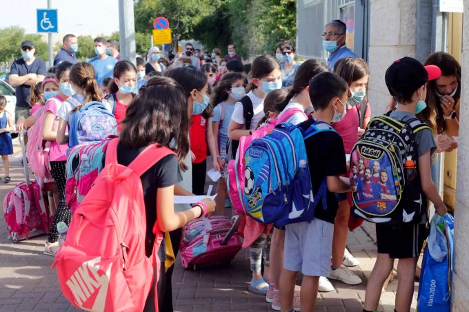 Junge Schülerinnen mit Mundschutzen sind vor einer Schule zu sehen. Coronavirus - Israel