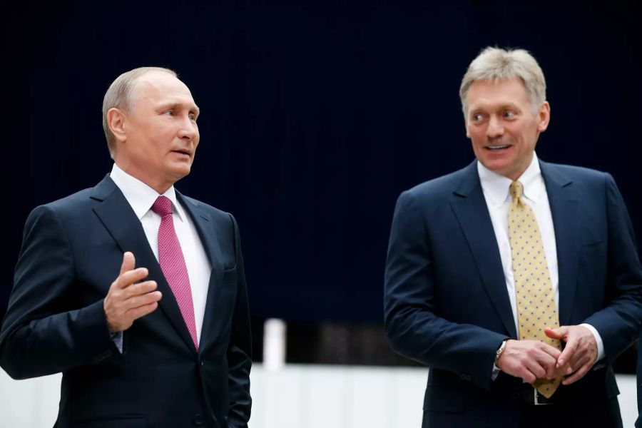 Wladimir Putin (l.), Präsident von Russland, spricht neben seinem Sprecher Dmitri Peskow.