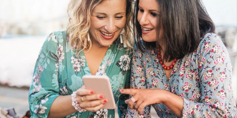 Zwei Frauen schauen auf ein Smartphone.