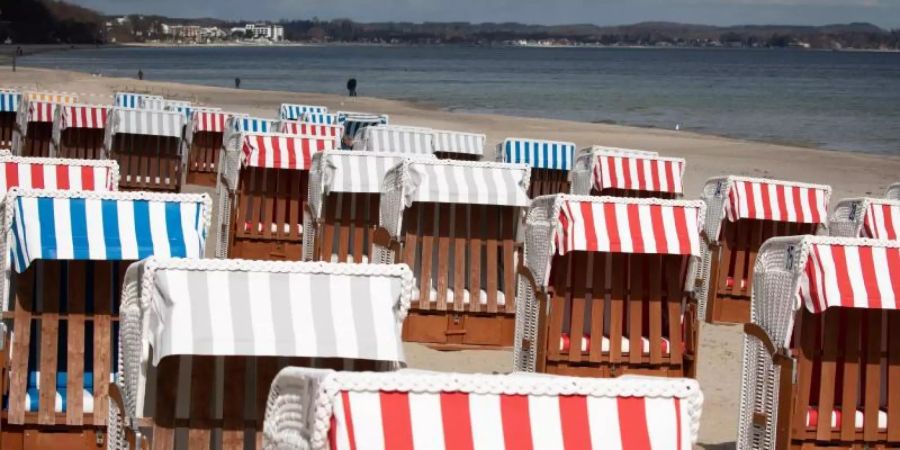 Geschlossene Strandkörbe stehen auf dem fast menschenleeren Strand in Timmendorfer Strand an der Ostsee. Ab dem 17. Mai dürfen Geimpfte sowie Genesene und Getestete unter strengen Vorgaben in ganz Schleswig-Holstein in Beherbergungsbetrieben übernachten. Foto: Christian Charisius/dpa