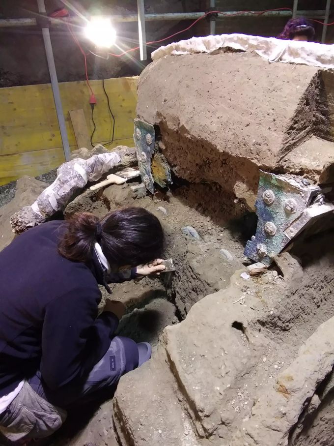 Eine Archäologin arbeitet am ausgegrabenen Triumphwagen. Triumphwagen mit erotischen Abbildungen in Pompeji ausgegraben