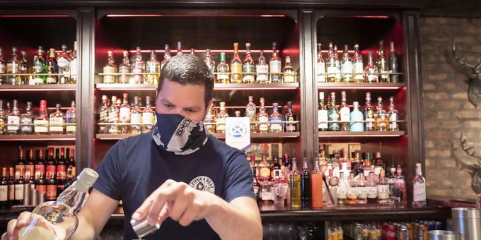 Ein Barkeeper serviert während der Pandemie des Coronavirus einen Whisky in einem schottischen Pub. coronavirus schottland