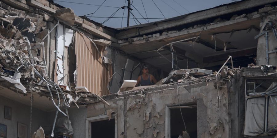 Ein Mann reinigt eine nach russischem Beschuss zerstörte Wohnung. Foto: Kostiantyn Liberov/AP/dpa