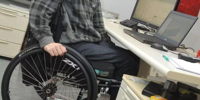 Ein Mann mit Rollstuhl an seinem Arbeitsplatz Ein Mann mit Rollstuhl an seinem Arbeitsplatz