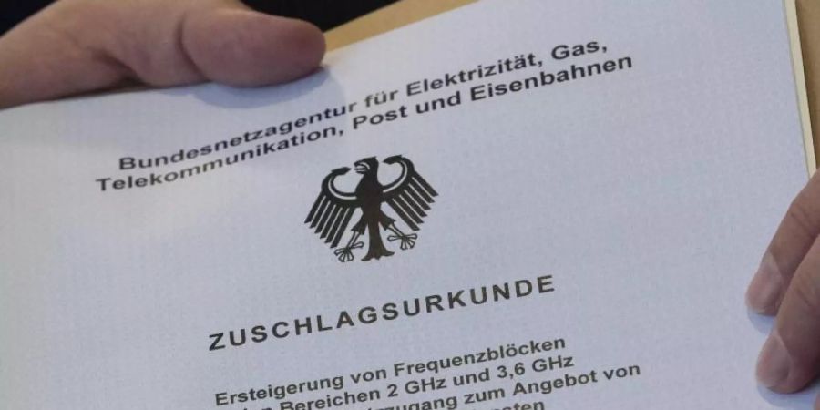 Die offizielle «Zuschlagsurkunde» wird dem Vertreter eines Mobilfunkunternehmens in den Räumen der Bundesnetzagentur übergeben. Foto: Boris Roessler