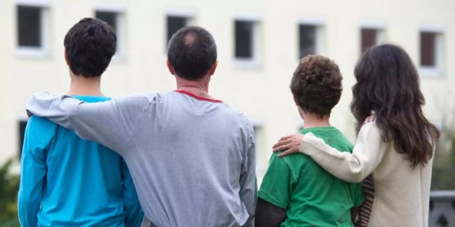 Eine syrische Familie sitzt vor einem Asylwohnheim der Zentralen Ausländerbehörde des Landes Brandenburg. Foto: Patrick Pleul/zb